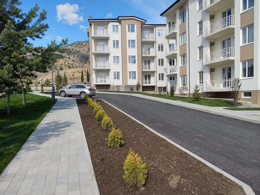 Двор жилого комплекса в Крыму: свежий асфальт, борт, плитка и ряды молодых можжевельников