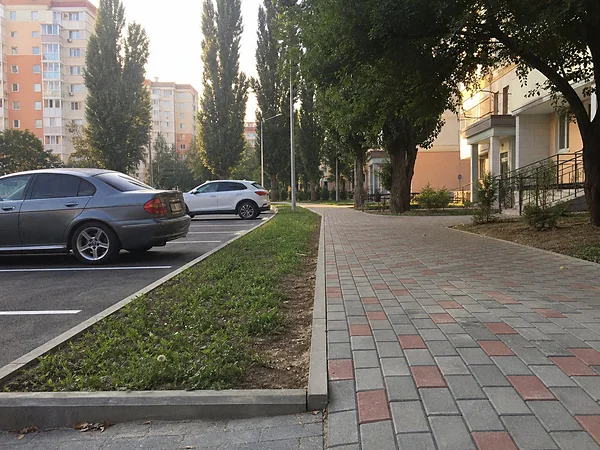 Пешеходный маршрут из плитки с красным акцентом вдоль парковки у жилого дома на юге