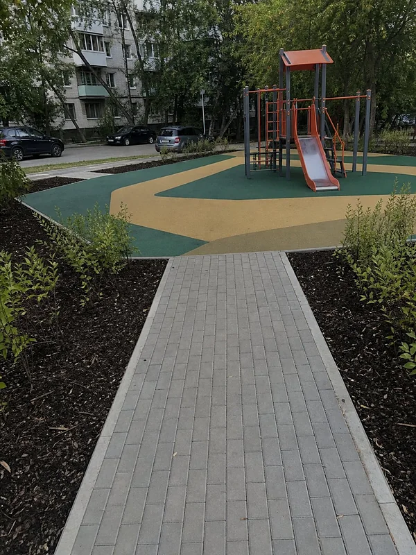 Детская площадка с травмобезопасным покрытием и плитка-тротуар между газонами
